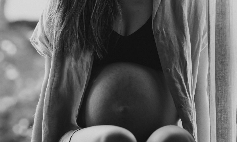 Schwangere sitzt im Fenster